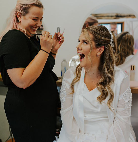 makeup artist and bride laughing together on wedding morning