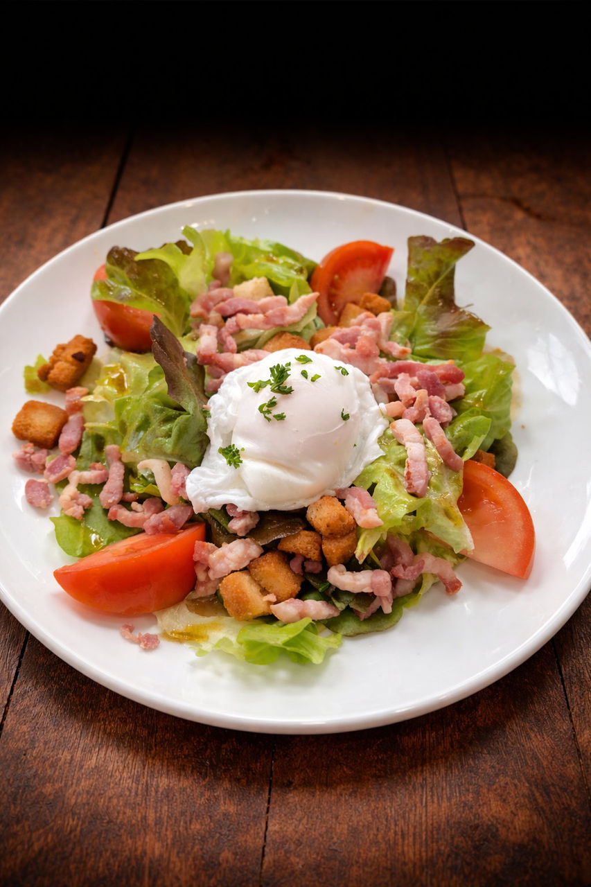 Salade composée avec œuf poché, lardons, croûtons et tomates fraîches