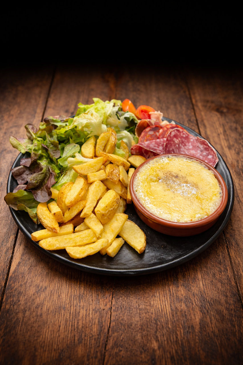 Assiette de camembert rôti accompagné de frites croustillantes, salade fraîche et charcuterie