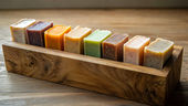 Collection de savons artisanaux aux couleurs variées alignés dans un support en bois naturel