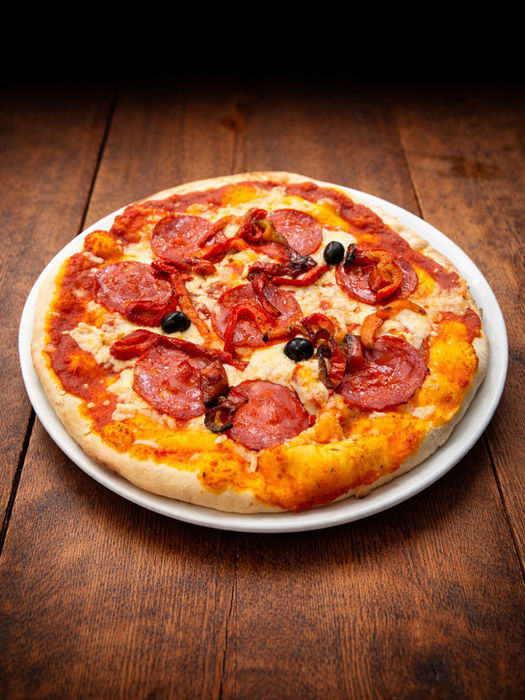 Pizza garnie de chorizo, poivrons grillés et olives noires sur pâte dorée