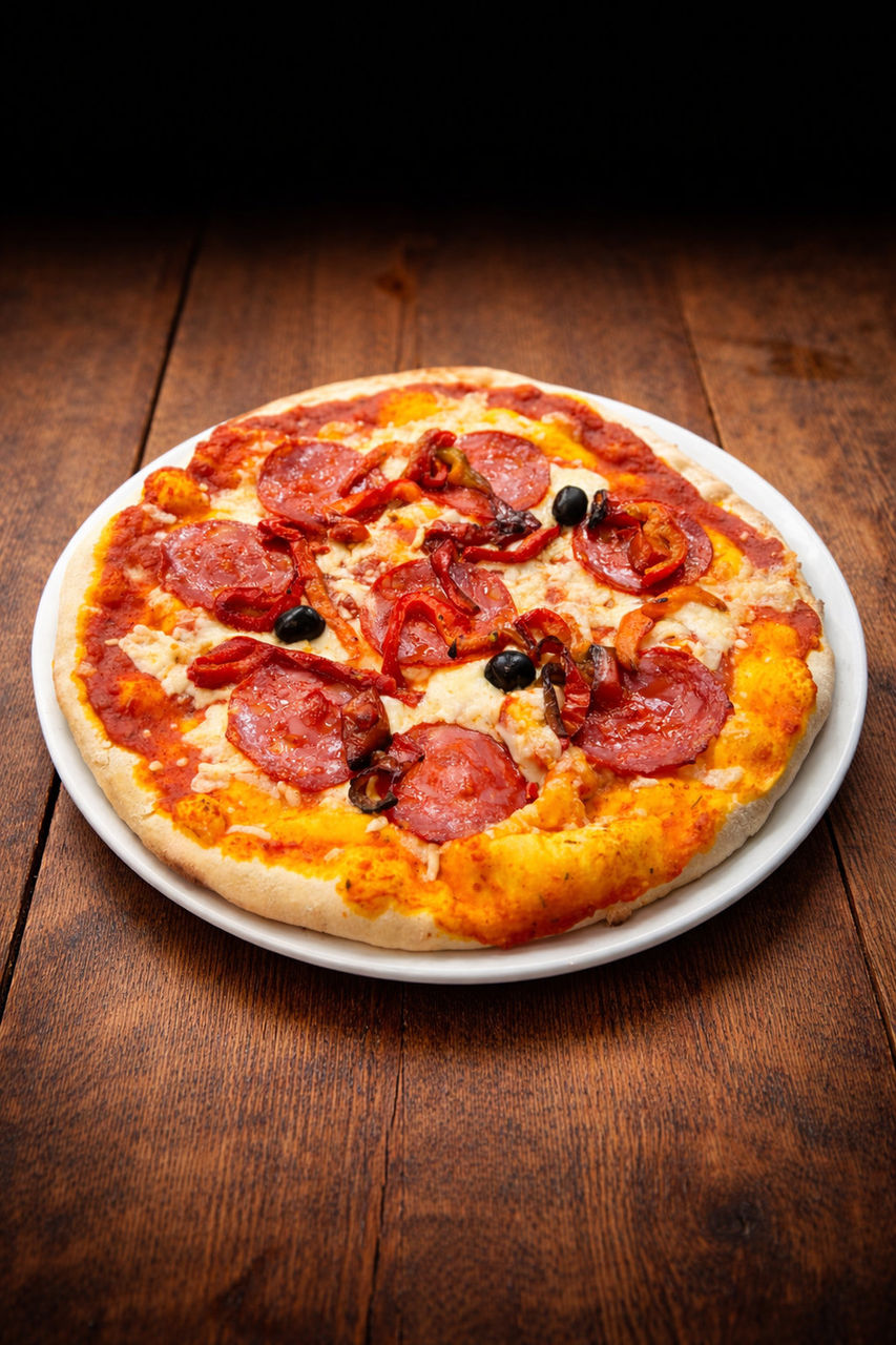 Pizza garnie de chorizo, poivrons grillés et olives noires sur pâte dorée