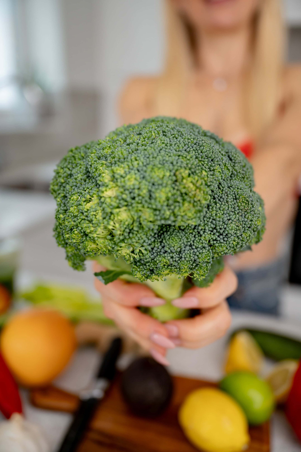 Holistically Balanced Blonde holding fresh broccoli toward the camera during her nutrition coach brand photoshoot in North Wales.
