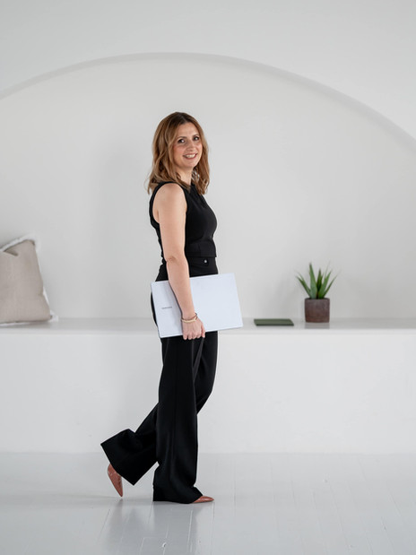 Female entrepreneur walking shot during a personal brand photoshoot, holding a laptop, captured mid-stride in a bright white studio.