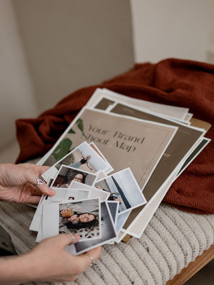 Brand shoot map in background of photographer fanning out client photos - showing off document created with Done for You Doc Generator automation system.