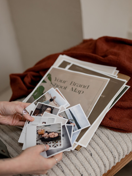 Brand shoot map in background of photographer fanning out client photos - showing off document created with Done for You Doc Generator automation system.