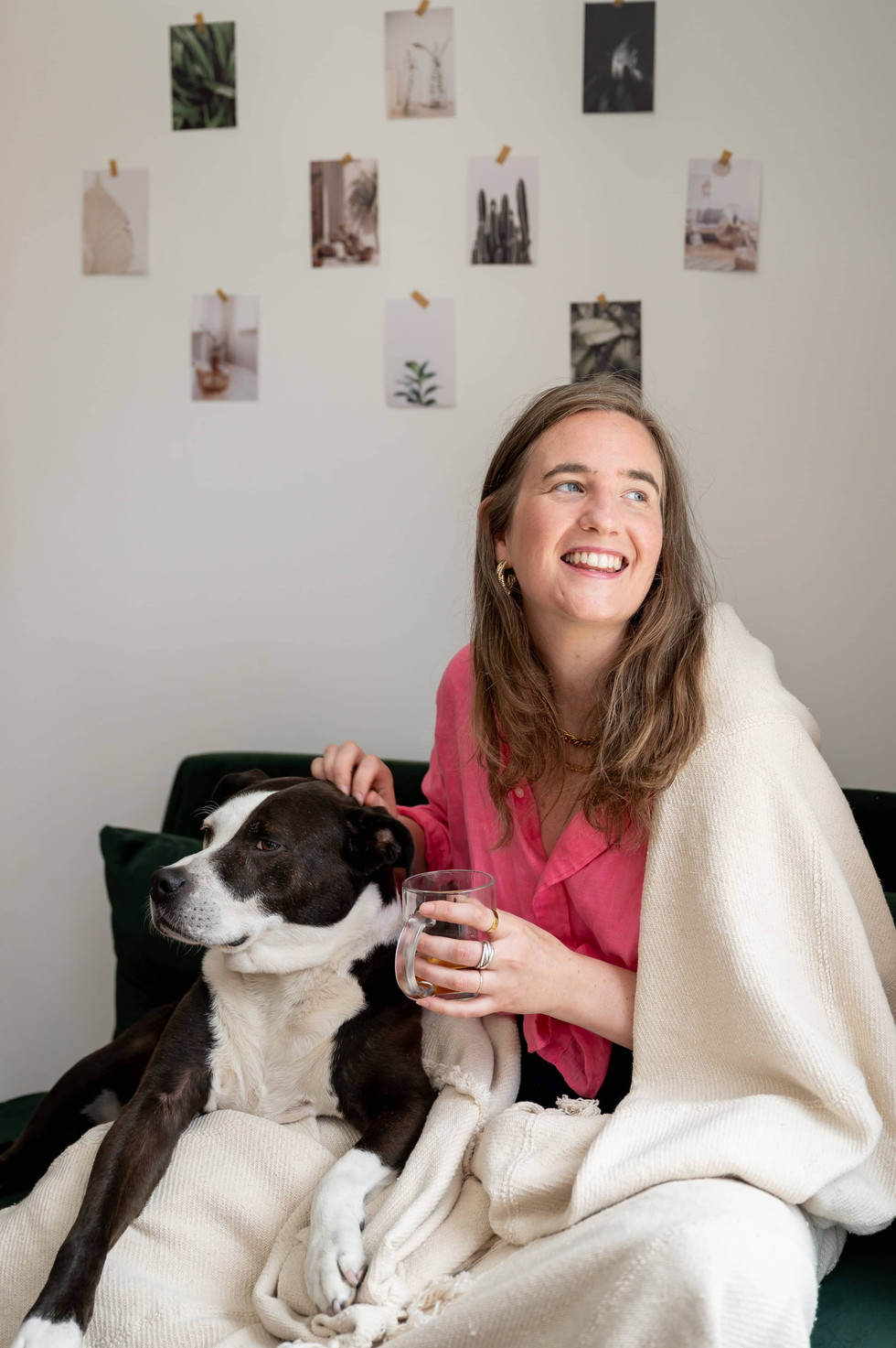 Therapist in pink shirt on coach drinking tea while stroking staffie.
