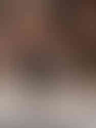 A woman in a black sleeveless top and pants poses with one leg raised against a brick wall background, captured by Liverpool brand photographer.