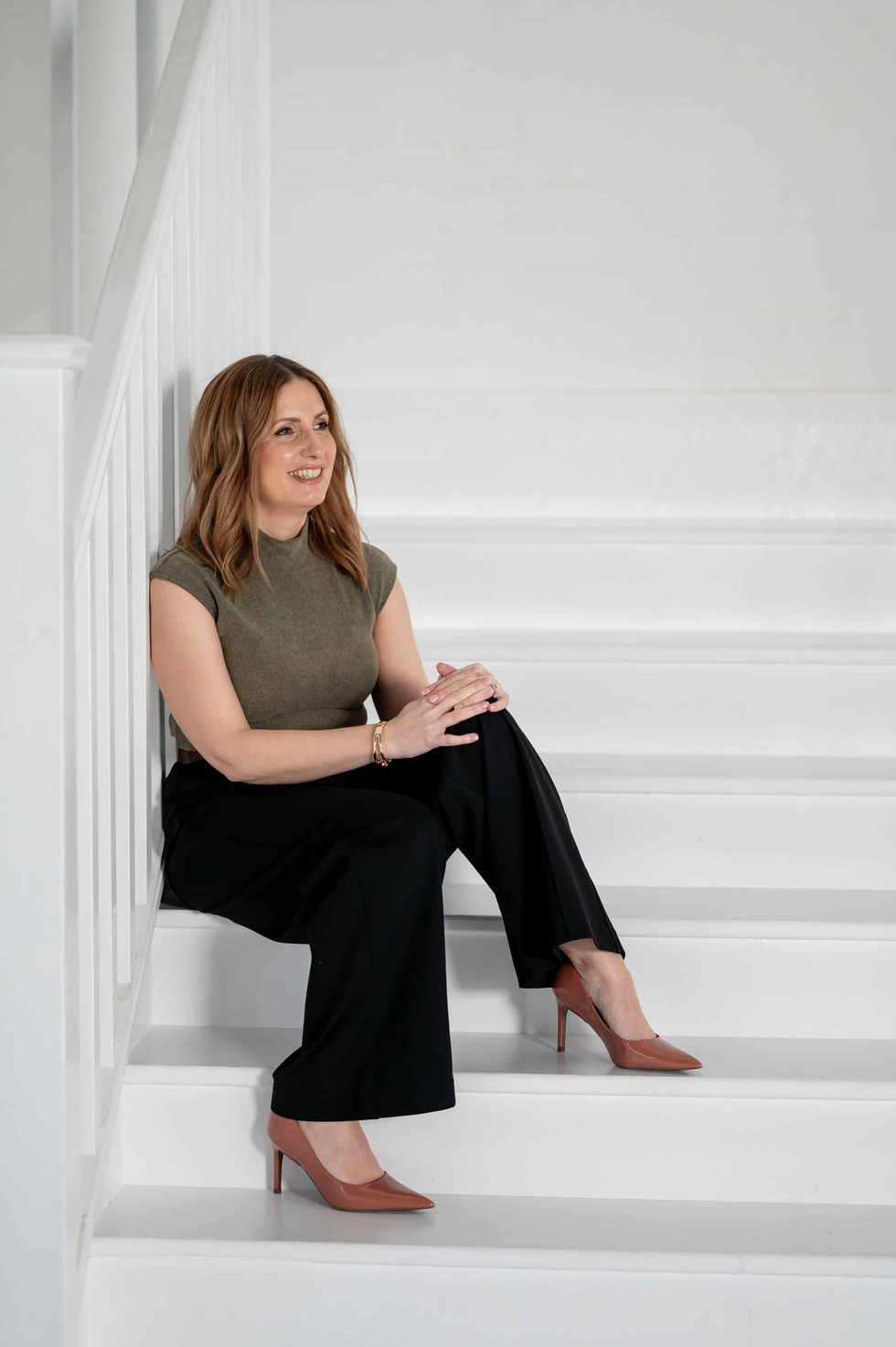 Professional portrait of Coaching for Procurement founder seated on white steps, conveying quiet confidence.