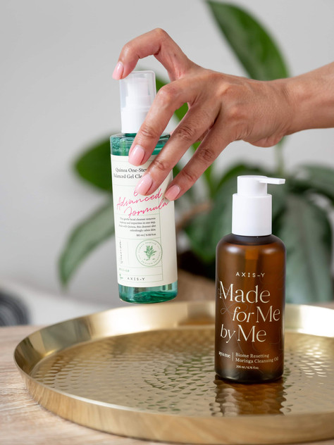 Hand placing two luxury skincare bottles on a gold tray during an Abeni Lane Skincare founder brand photoshoot in Liverpool.
