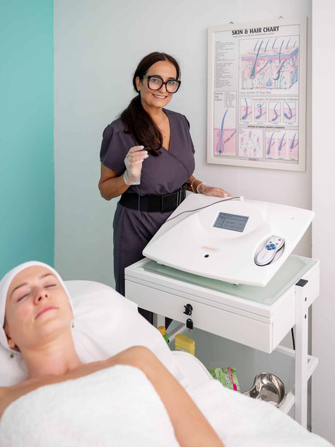 A skincare specialist at Revitalaser clinic in Wirral preparing for a facial treatment with a client lying comfortably under a towel.
