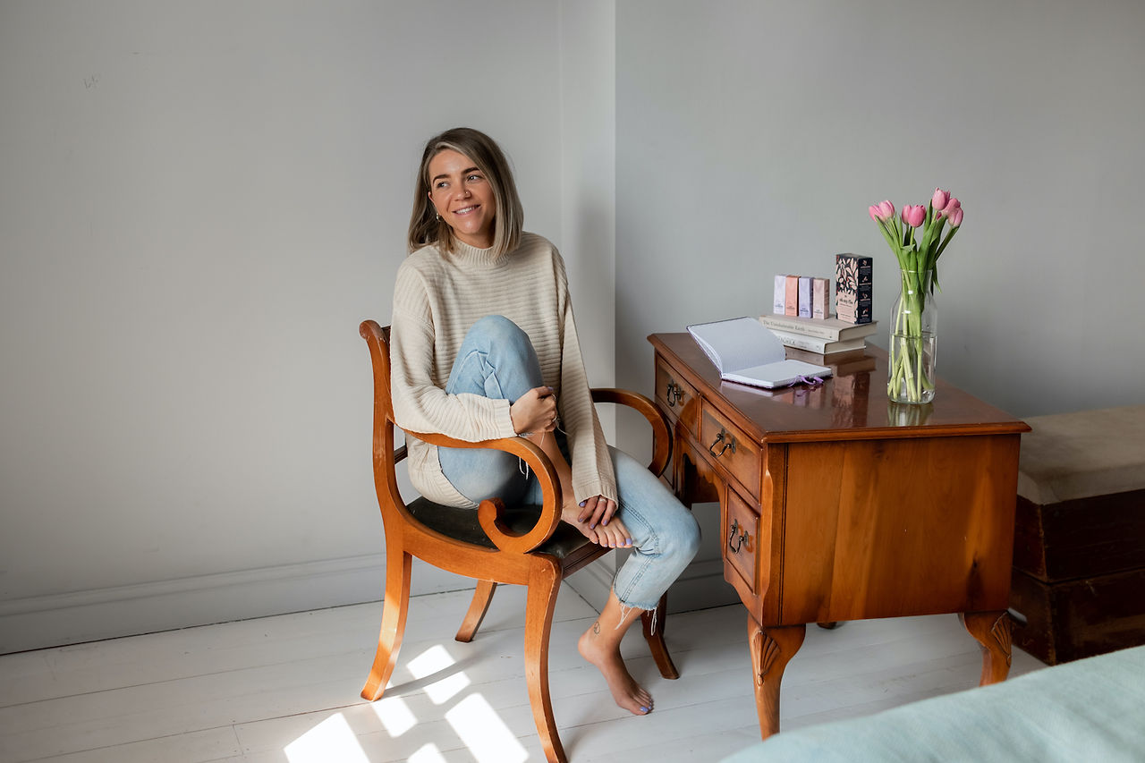 Founder of Our Remedy CBD sat at desk barefoot with journal and products in front of her.