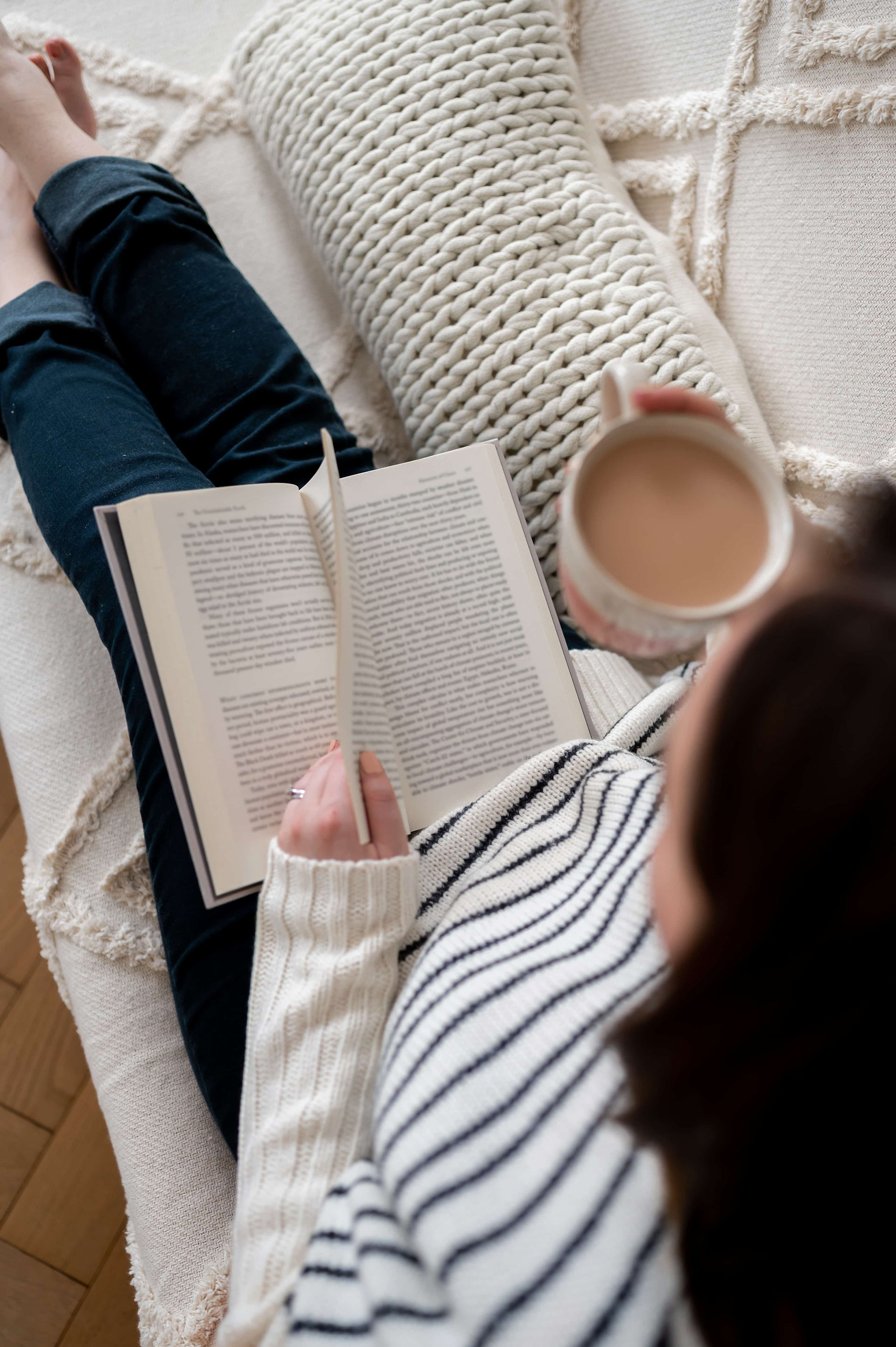 Manchester psychologist reading on couch with tea.