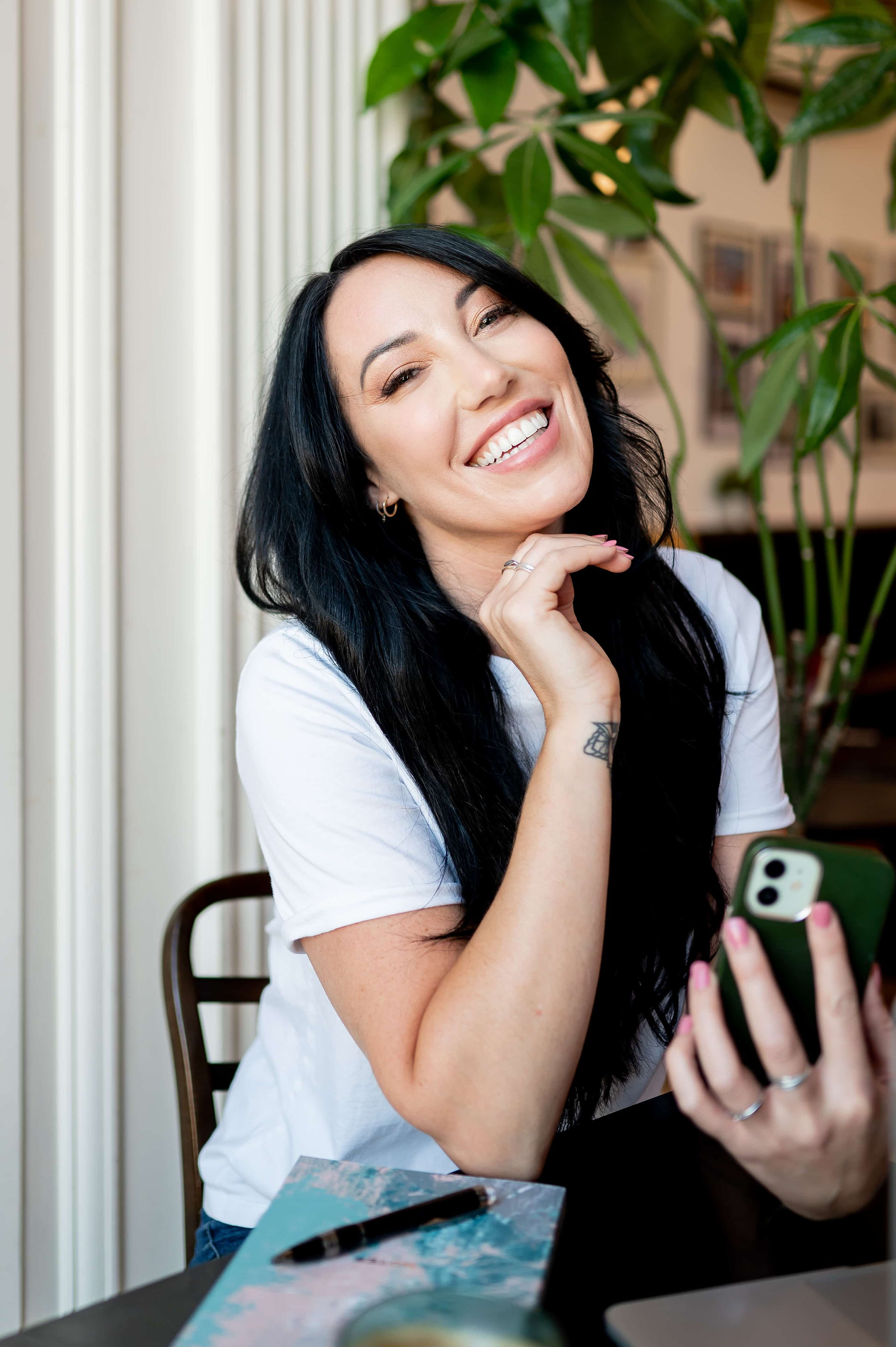 Hypnotherapist holding phone while smiling at the camera.