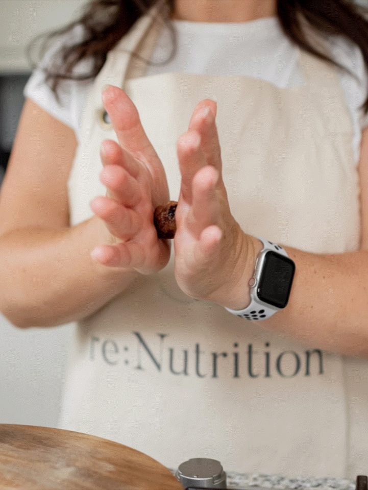 Stop motion close up of close-up of hands rolling a vegan protein ball in branded apron during wellness shoot.
