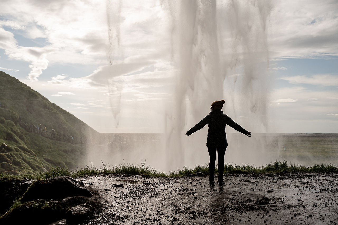 A digital nomad photographer capturing marketing expert's personal brand photography session under Seljalandsfoss Iceland.