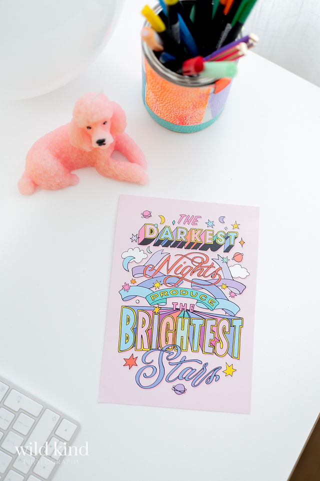 Flatlay with colorful Liz Harry print and pink poodle candle in London home.
