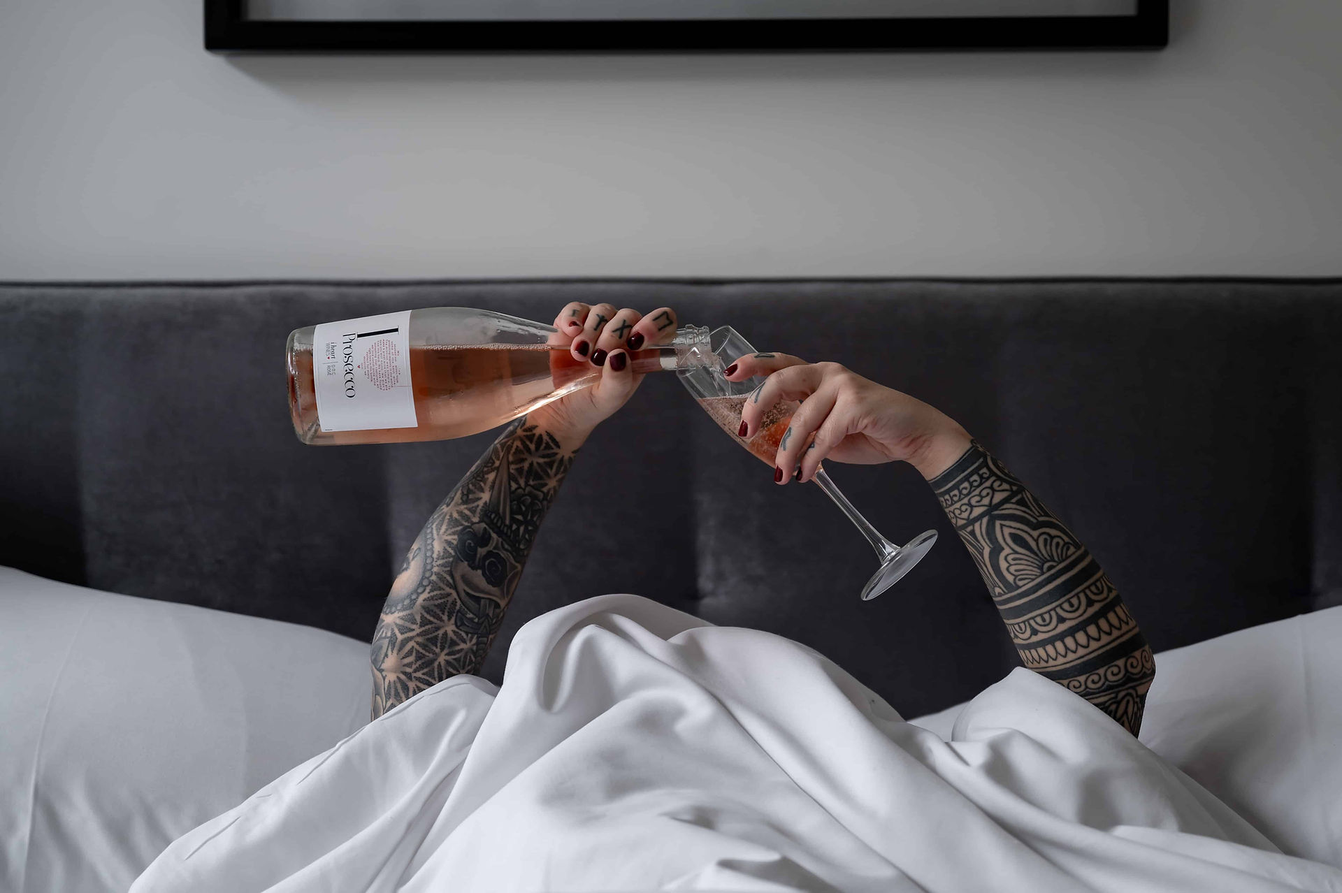 A woman in bed with a bottle of wine during a personal brand photoshoot.