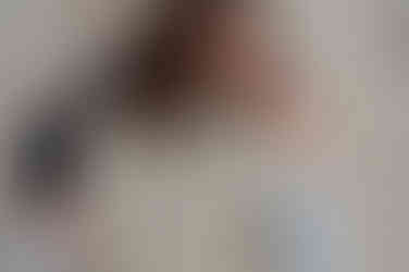 A woman sits on a sandy surface, holding a large circular mirror that reflects the ground beneath, capturing the moment with the expertise of a Liverpool brand photographer.