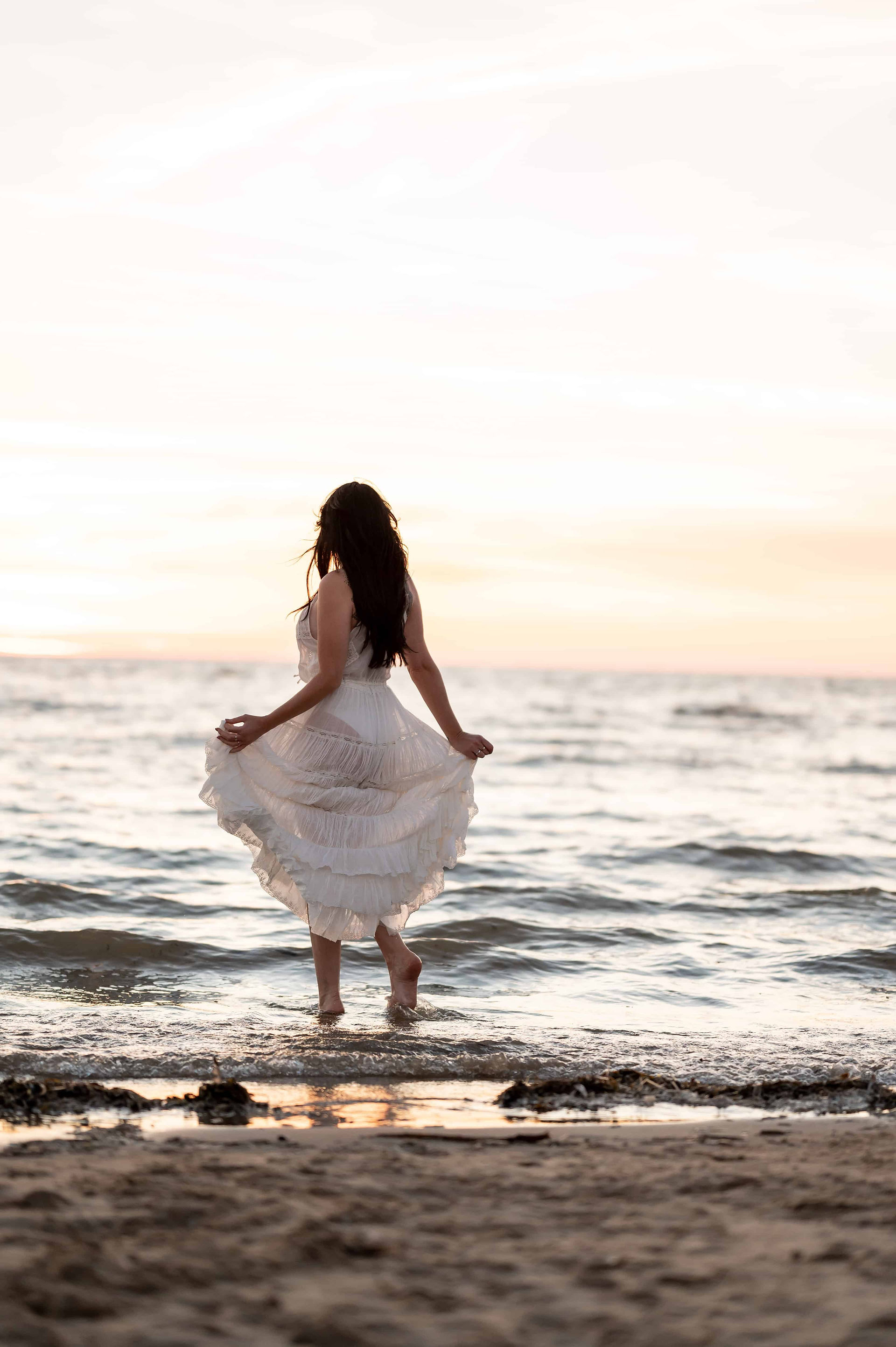 Hypnotherapist in white dress in water at Ainsdale Beach.