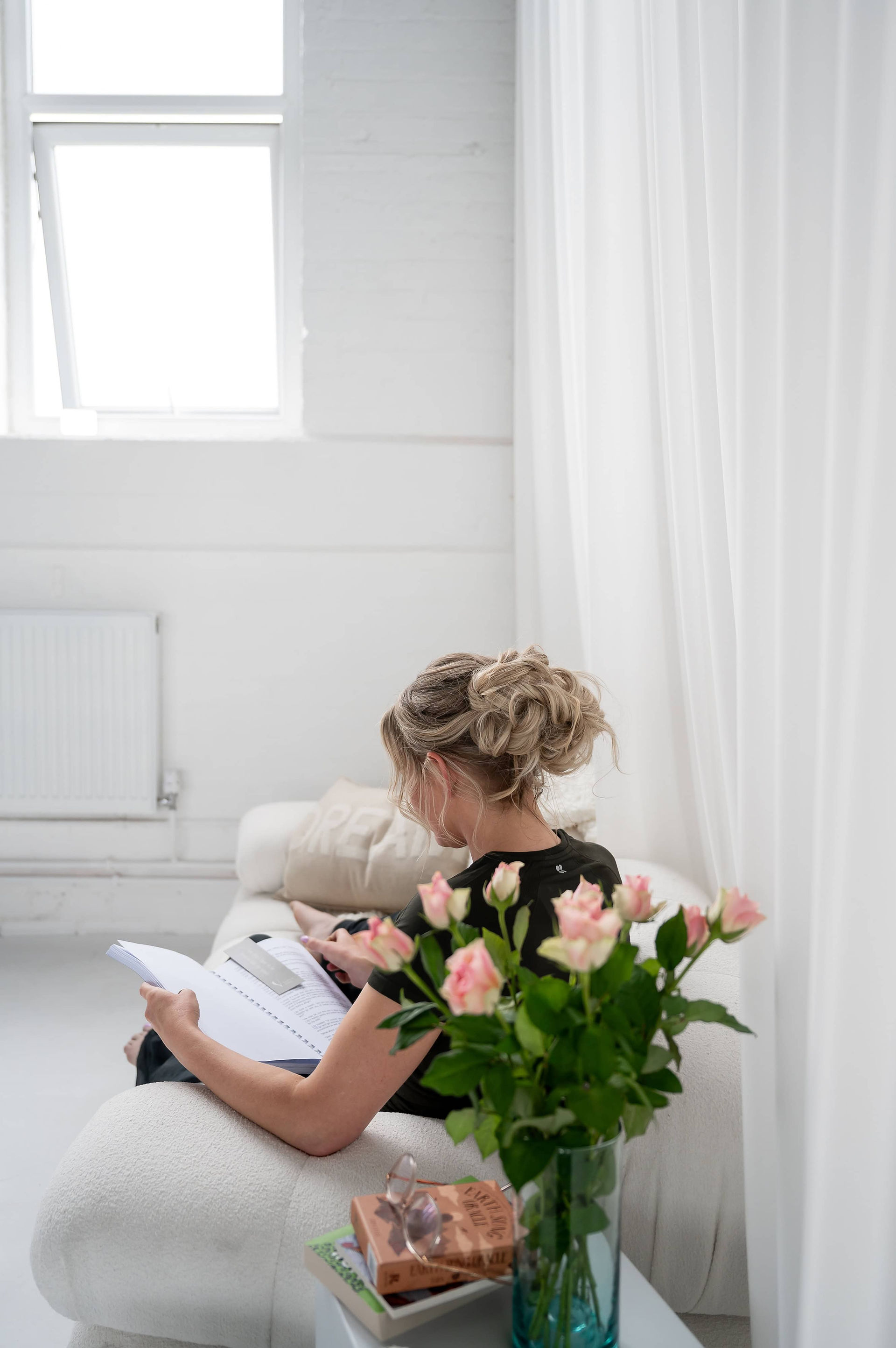 Emily writing and planning next to bouquet of pink flowers at No Filter Studios
