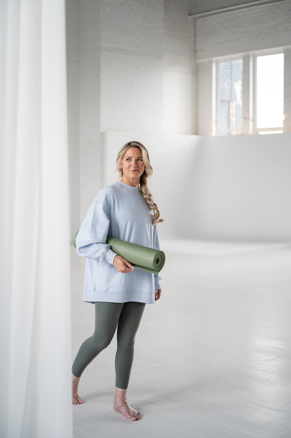 Emily walking barefoot through No Filter Studios holding a yoga mat