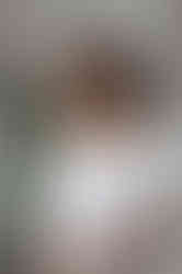 Woman in a white blazer laughing joyfully against a minimalist, plant-filled backdrop in a Wirral photo studio.