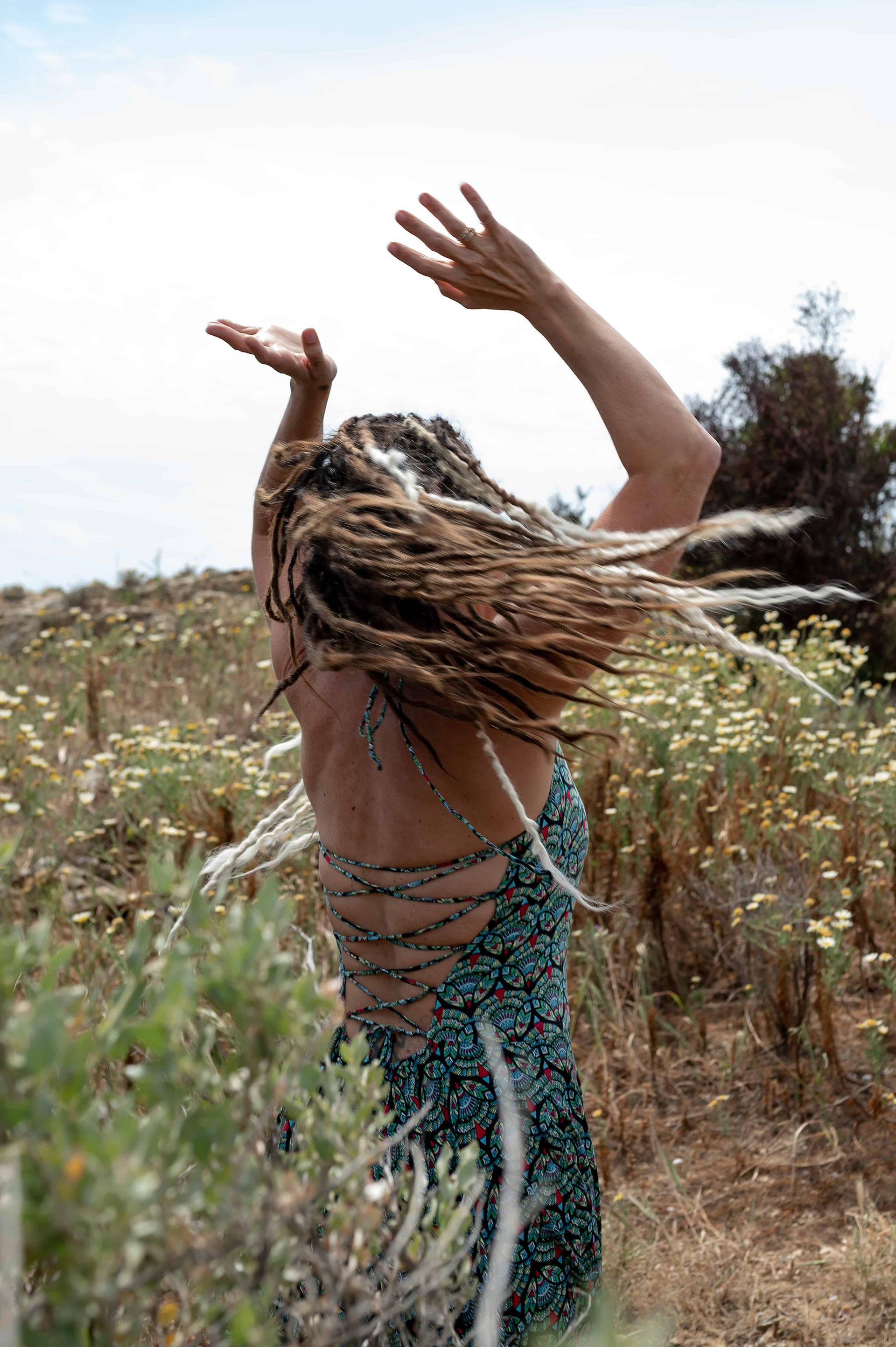 Enchanted Fields Festival creator, Chloe Ward, spinning in wildflower field, her dreads, going in all directions in a blur.