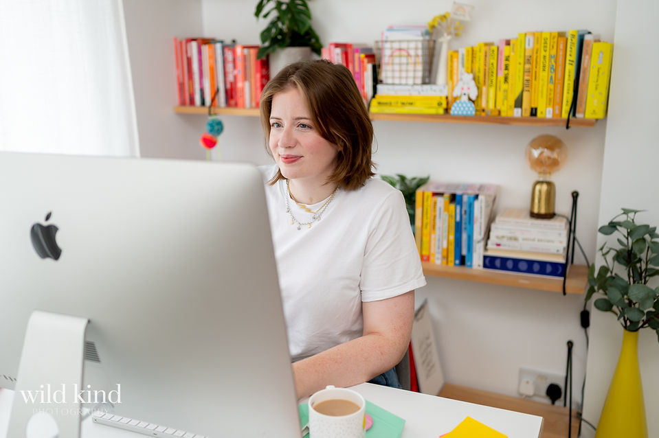 London marketing expert working on computer against background of books arranged by color.