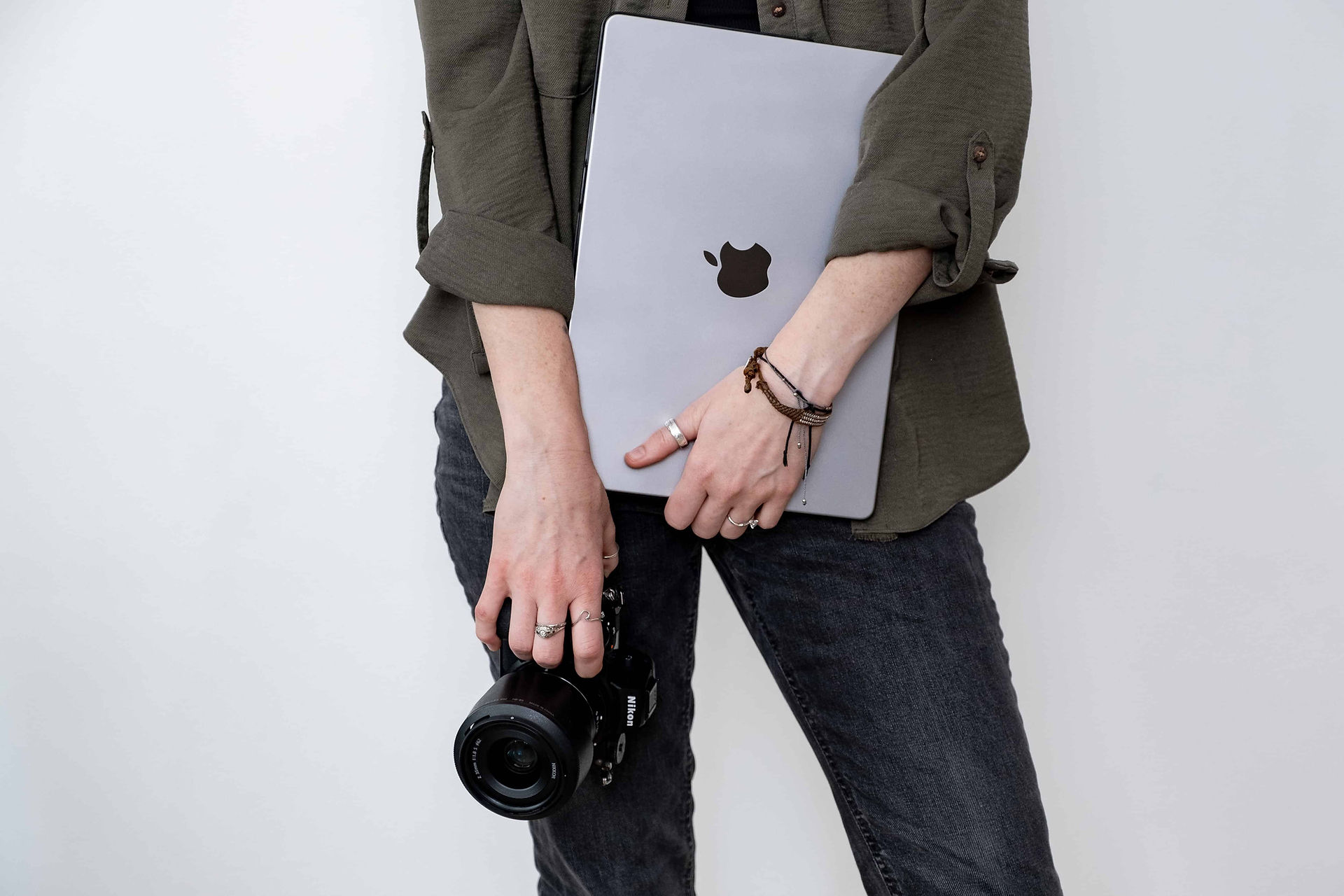 Brand photographer holding camera and laptop in front of her.