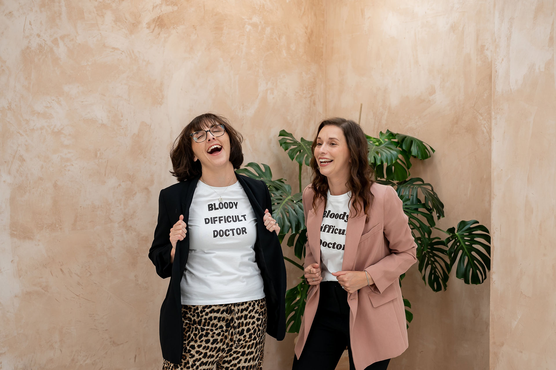 Dr. Chelcie Jewitt and Dr. Becky Cox from Surviving in Scrubs wearing blazers over shirts that say "Bloody Difficult Doctors," during their branding and content photoshoot at Haybeno Studios.