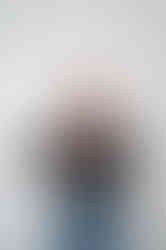 Brand designer laughs while opening a bottle of champagne in a minimalist studio.