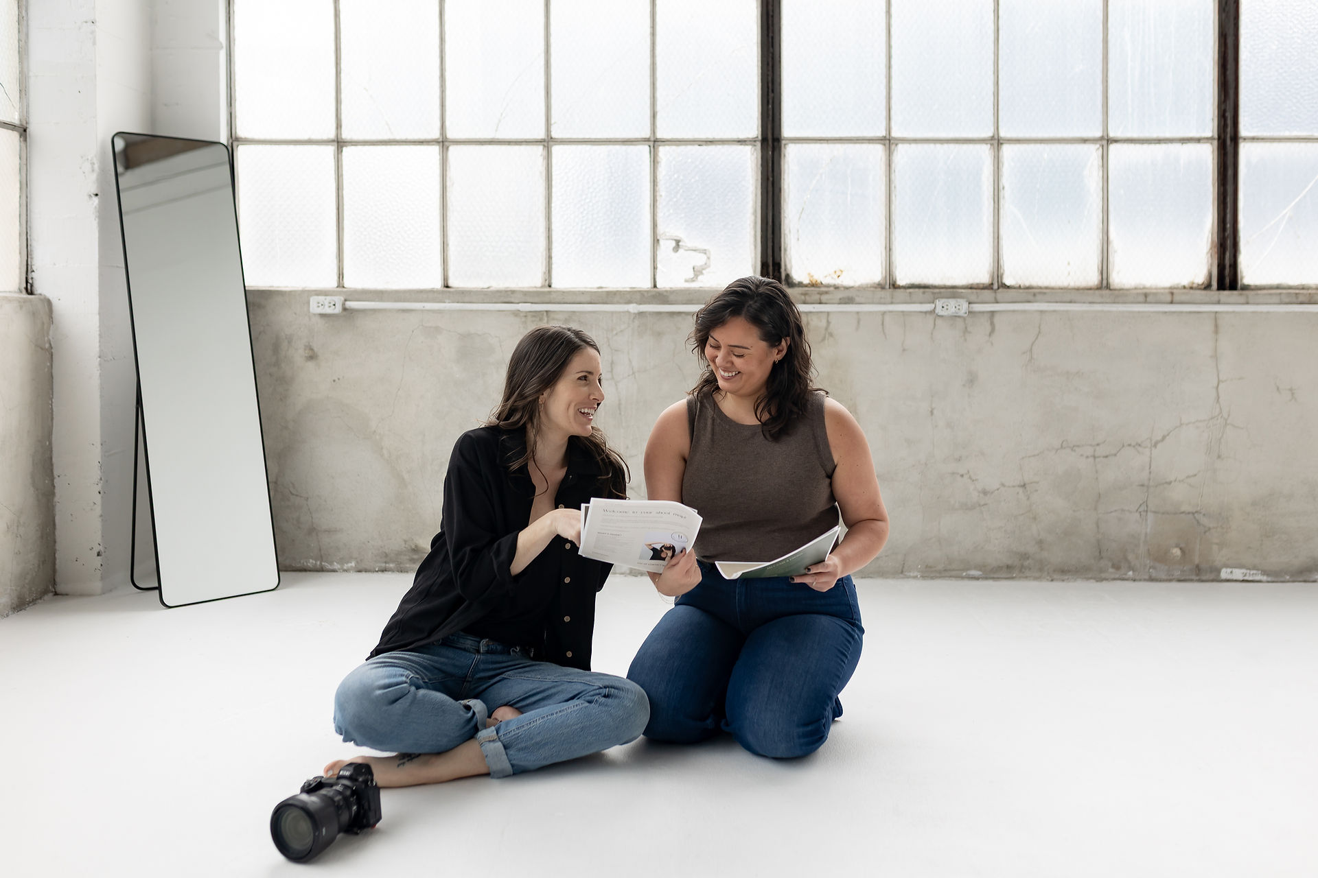 Photographer and client going over shoot plan in bright photography studio.