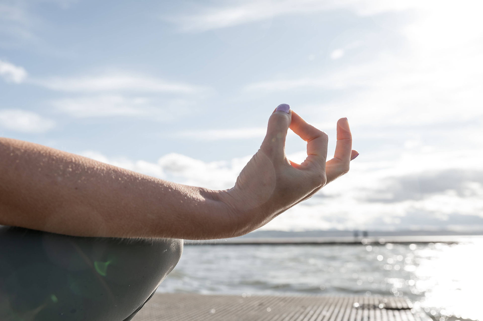 Close-up of hand in a mudra pose during yoga near the water