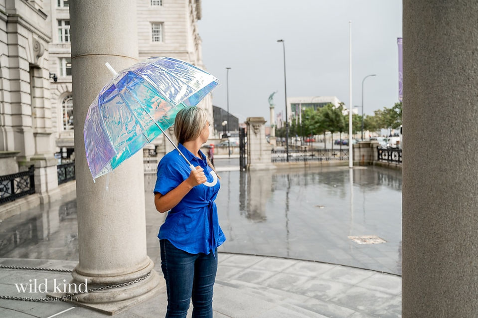 Property Investment expert in Liverpool under umbrella in rainstorm.