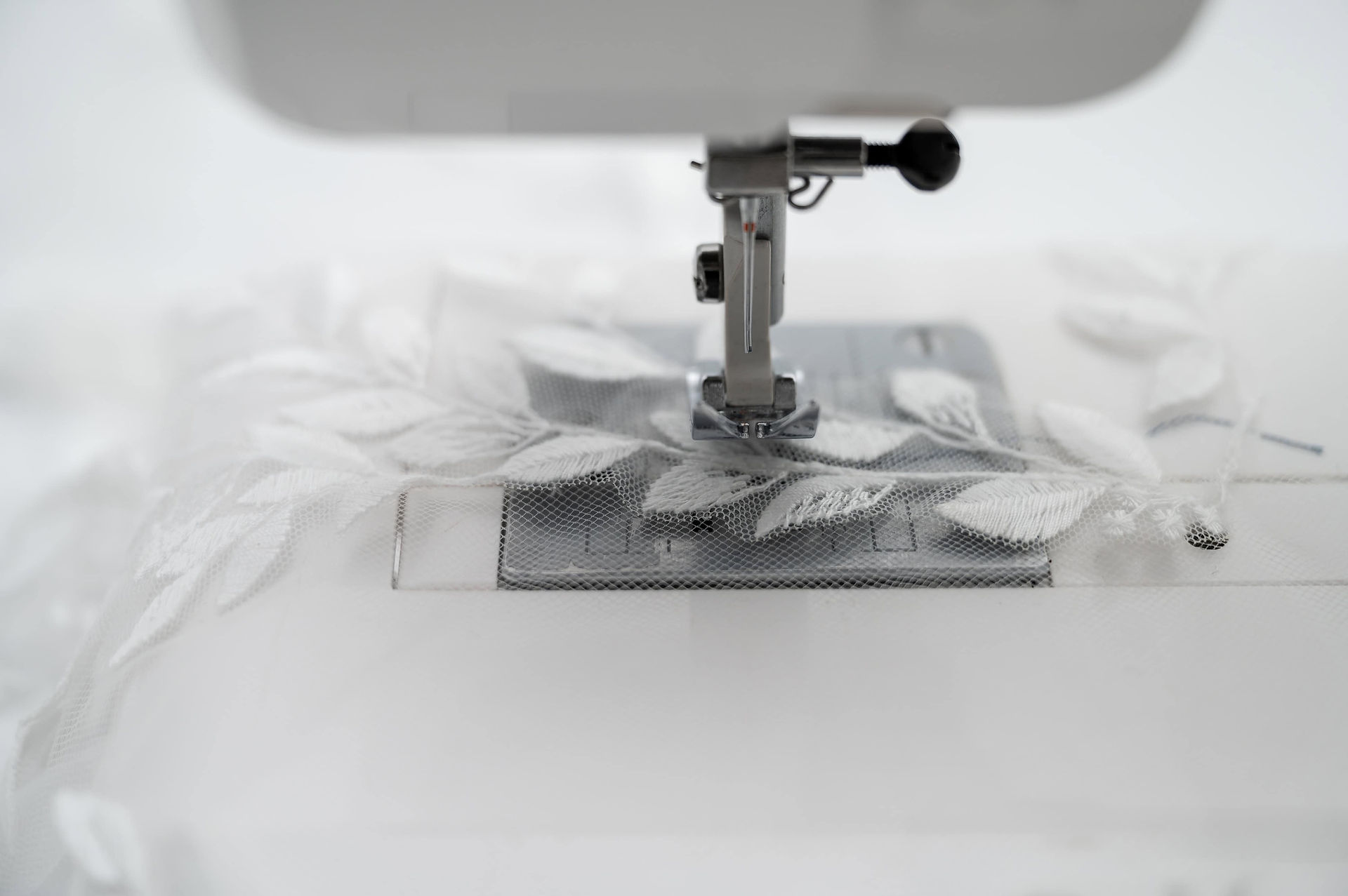 Close-up of lace being sewn under a machine at Redress Studio during a Liverpool wedding dress alterations photoshoot.