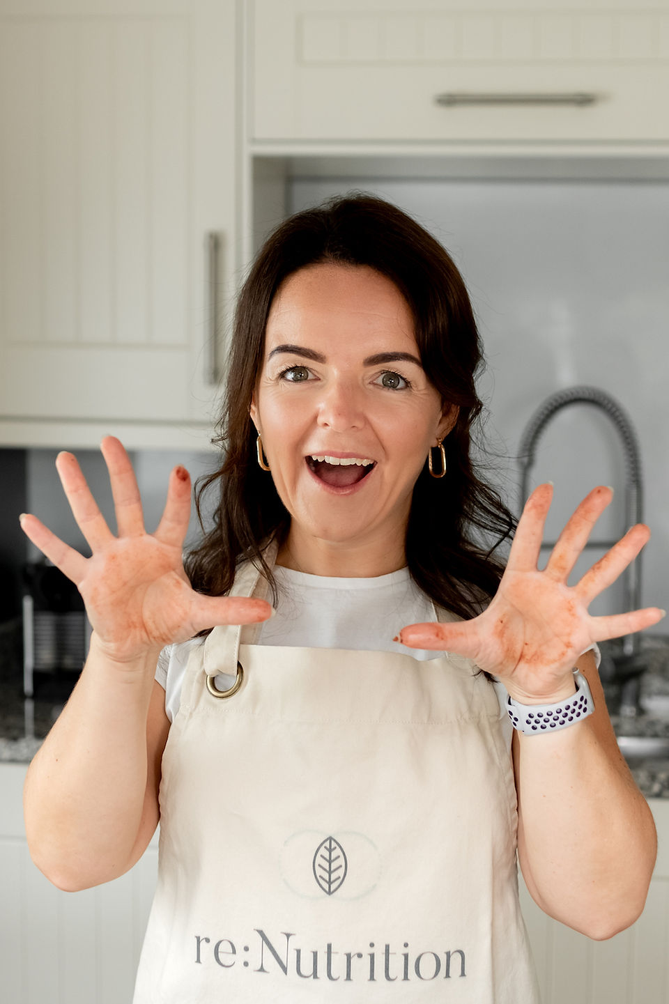 Functional health coach smiling during Liverpool brand shoot, hands open in apron.