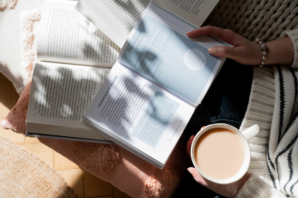 Woman reading lots of books on couch with bright shadows.