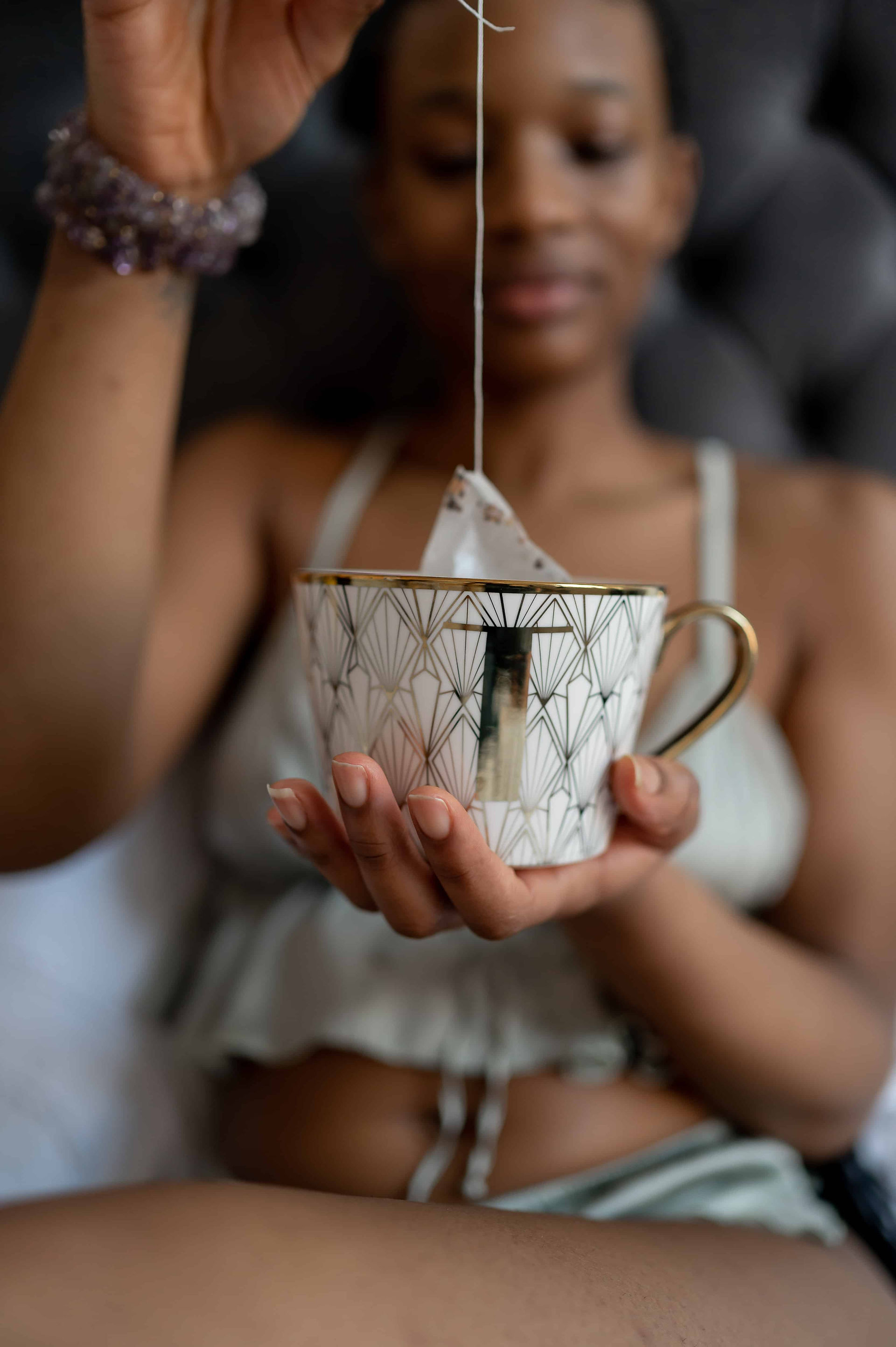 Woman relaxing and pulling teabag out of her mug.