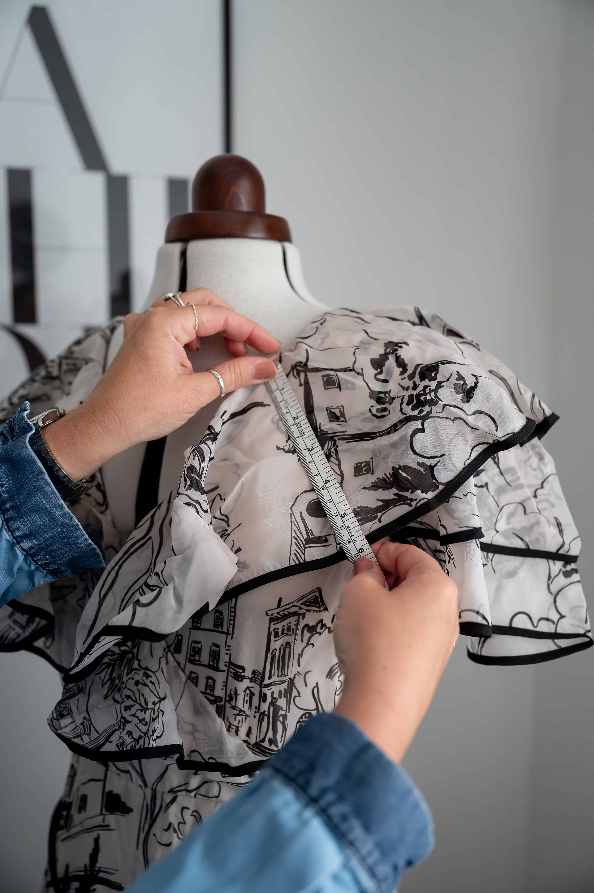Hands holding a ruler measuring the ruffled fabric of a dress on a mannequin, captured by Liverpool brand photographer.