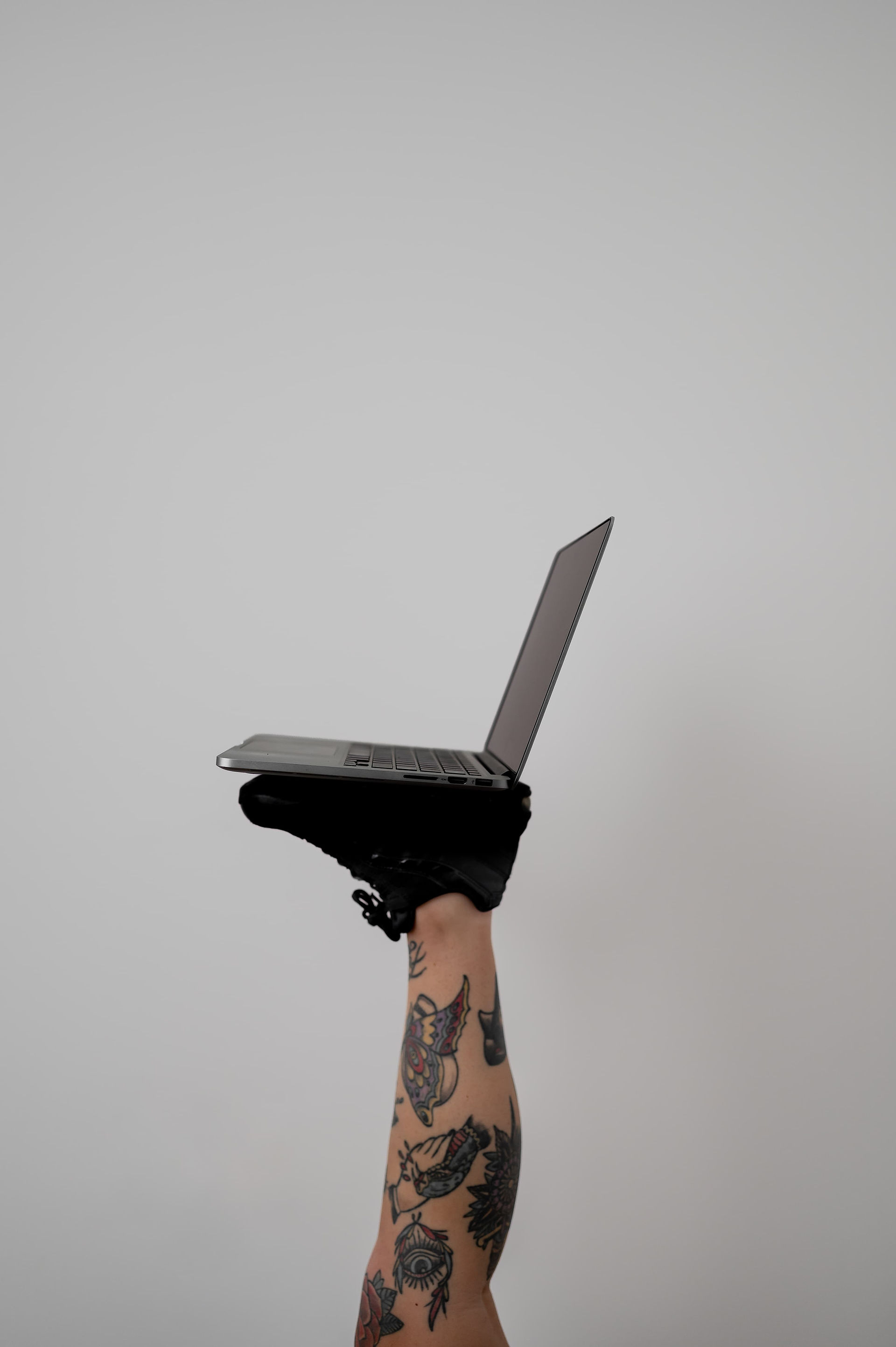 A tattooed woman's leg balancing a laptop on her foot.