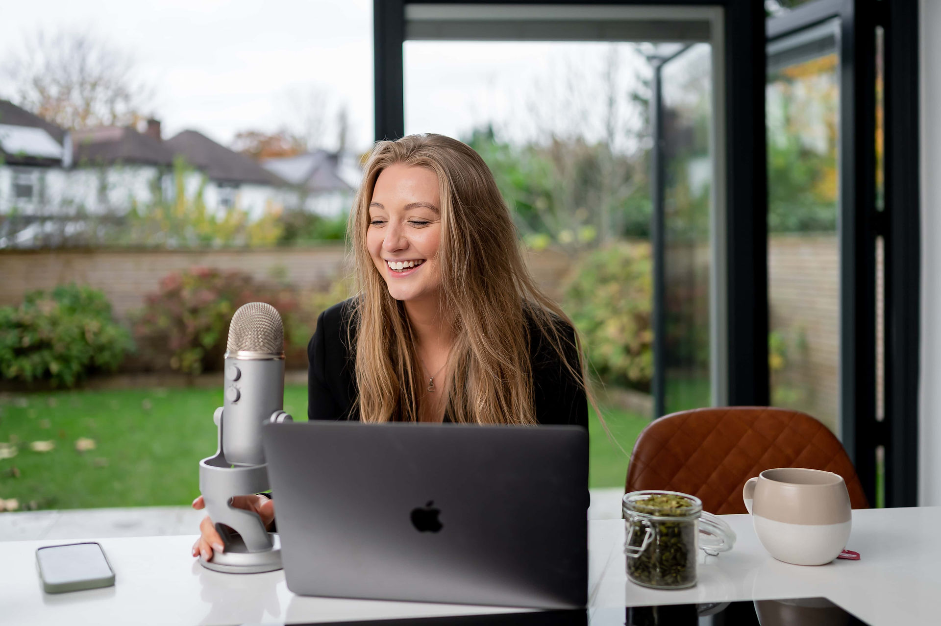 Manchester womens health coach, Sarah Elisabeth recording podcast in kitchen.