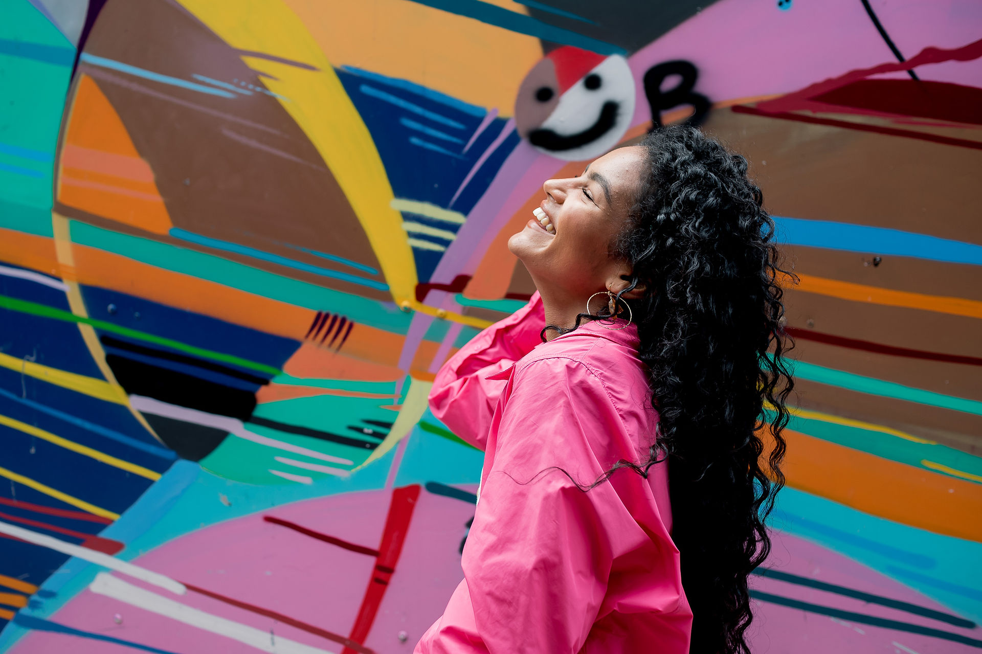 Woman laughing in front of colorful Liverpool wall
