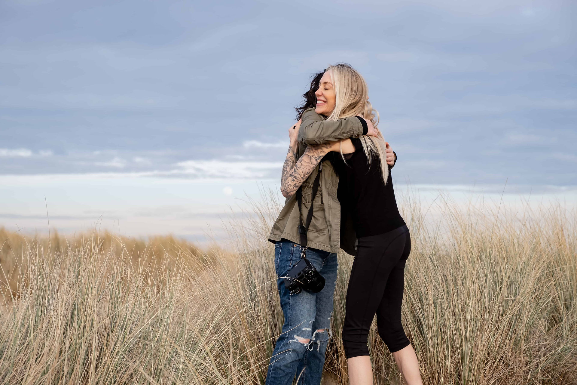 Photographer and client embracing during a beach brand session, highlighting connection-driven photography and authentic, natural interactions in Liverpool.