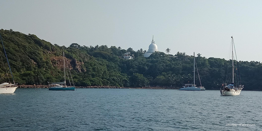 sailboats anchored below Buddhist shrine