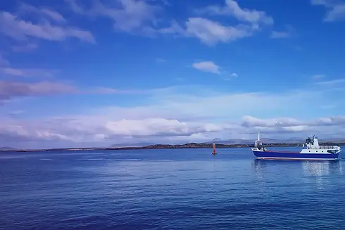 Blue ship sailing on calm sea under a partly cloudy sky