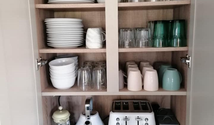 Organized kitchen pantry with dishes, glasses, and appliances