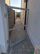 Metal gate ajar, revealing paved pathway