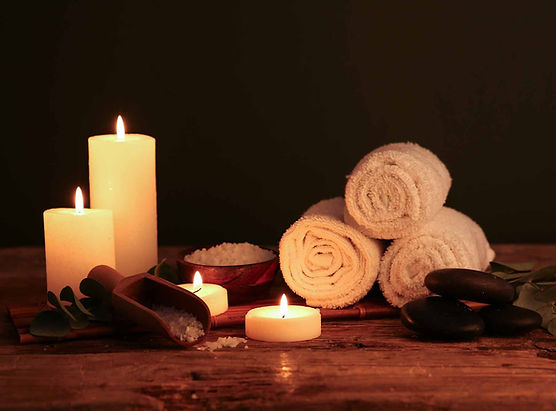 Lit candles, rolled towels, and spa stones for relaxing, D6wellness.