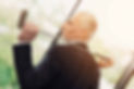 Man in suit holding a golf club, looking away; sunny background